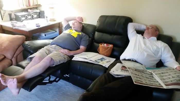 Two dads napping on recliners with newspapers, showcasing their humor and laid-back attitude.