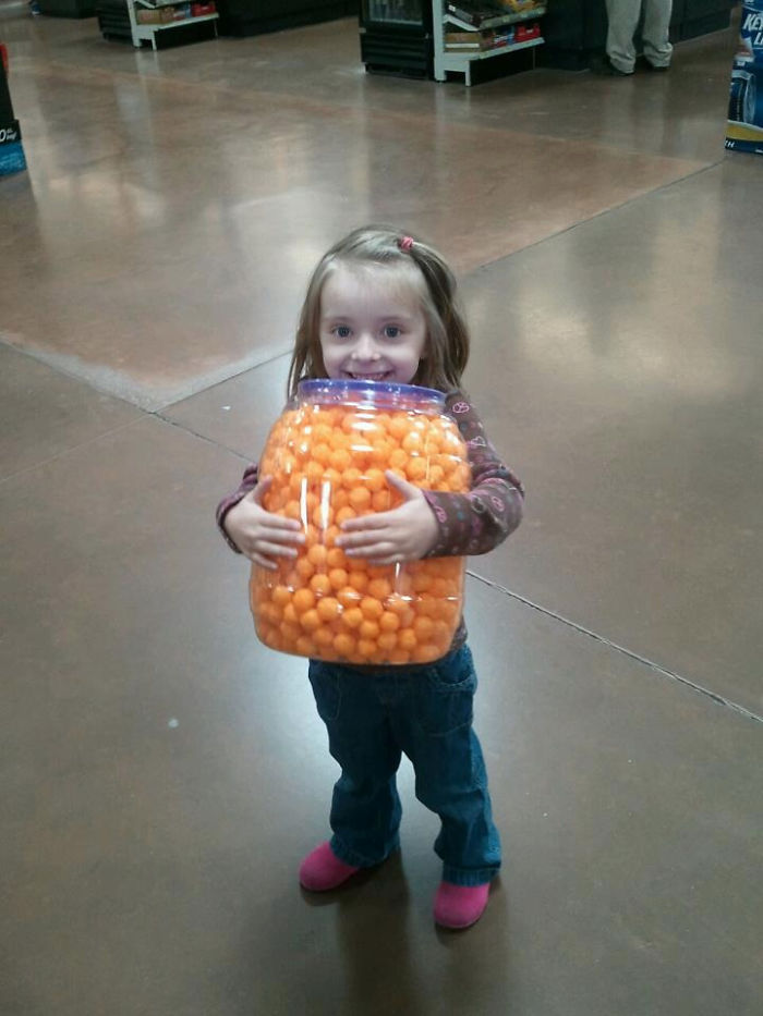 Child holding a large container of cheese balls, exemplifying dad jokes creativity.
