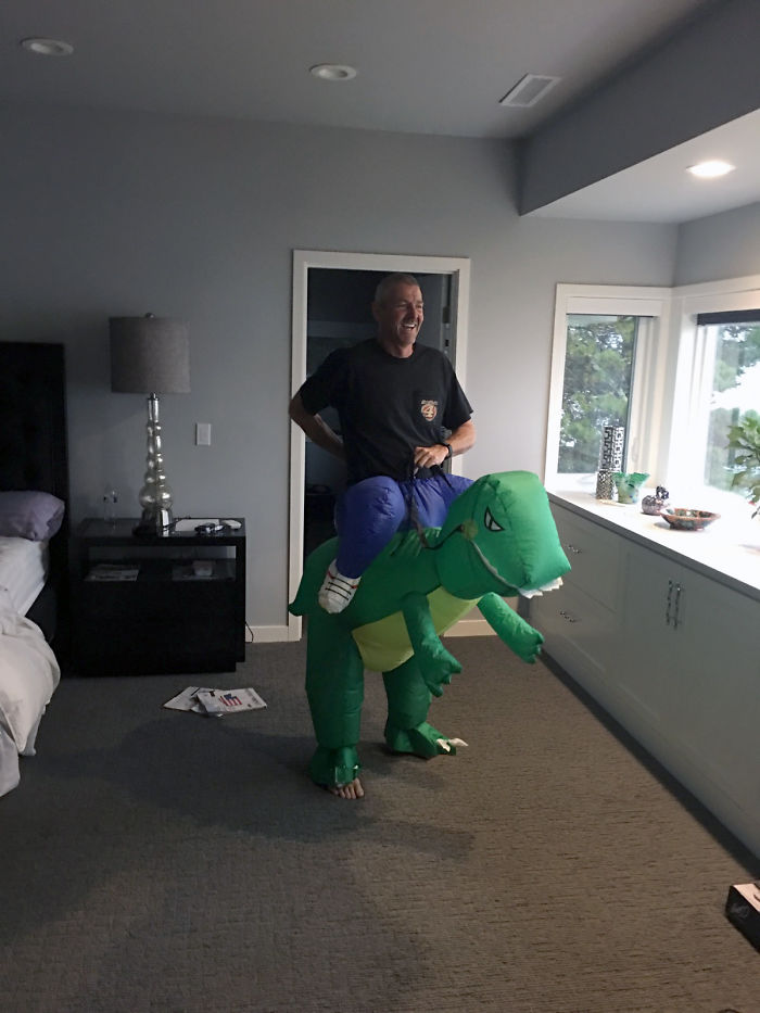 Dad in dinosaur costume, smiling and bringing humor to the room.