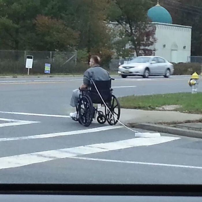 Man in a wheelchair crossing the street confidently, showing complete disregard for traffic.