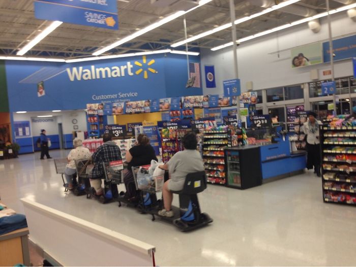 Four people on mobility scooters shopping at Walmart, seemingly relaxed and unconcerned.