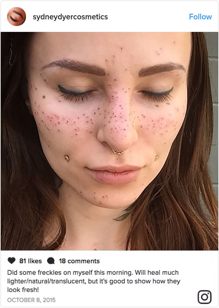 Woman with tattooed freckles, eyes closed, showcasing new beauty trend on her face.