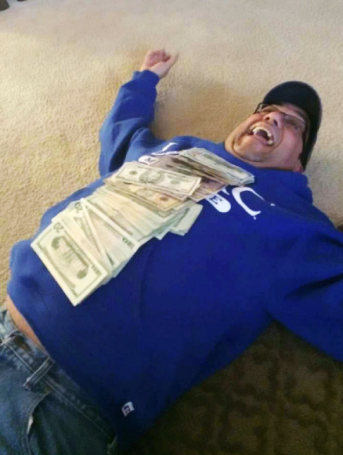 Dad lying on the floor laughing, covered in cash, showcasing his humorous side.