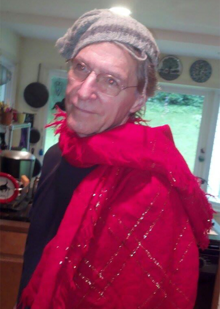 Dad wearing a gray hat and red scarf, humorously posing in a kitchen.