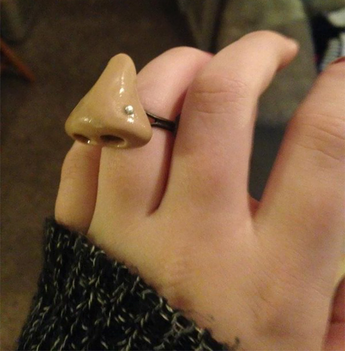 A hand wearing a novelty nose ring, displaying classic dad jokes taken to another level.