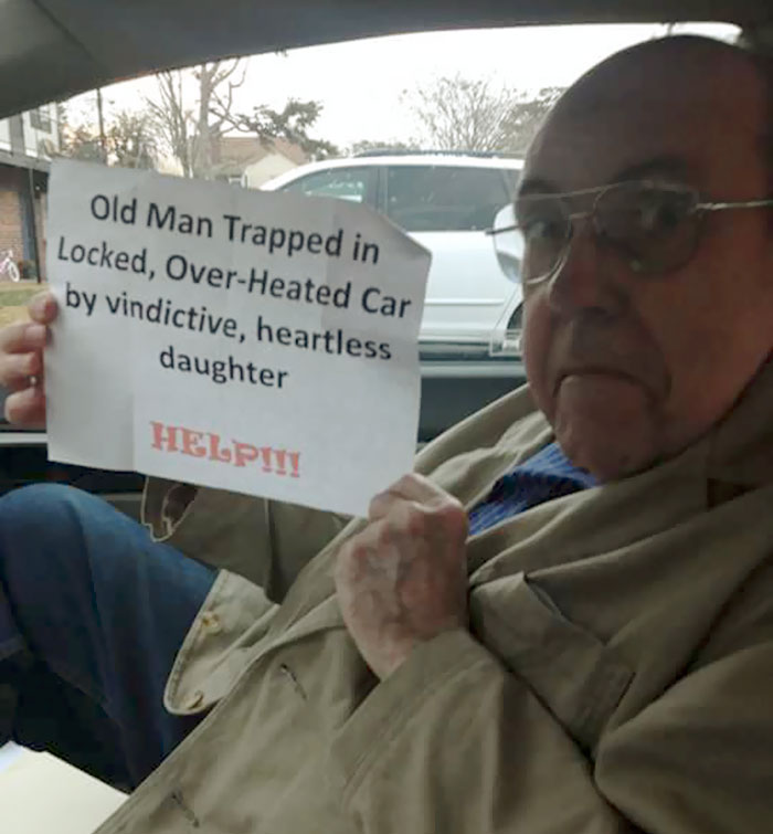 Dads taking jokes to another level, holding a humorous sign while sitting in a car.