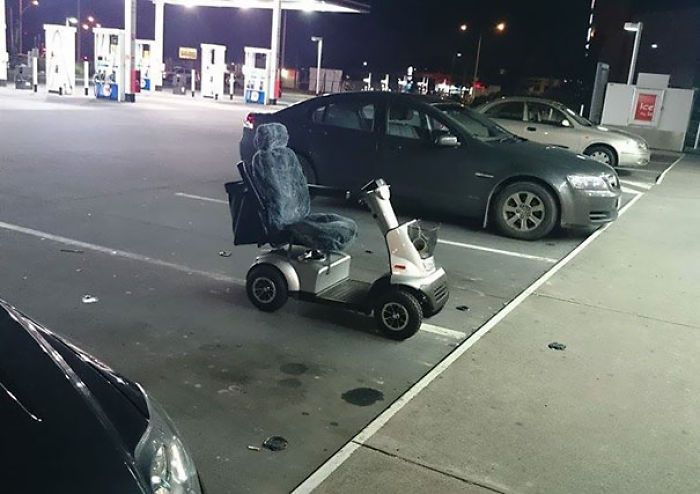 Mobility scooter parked in a car space at a gas station at night, showing someone who doesn't care.