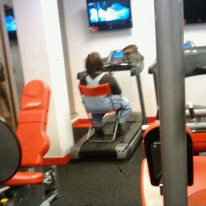 Person sitting on a treadmill facing a TV, embodying total disregard in a gym setting.