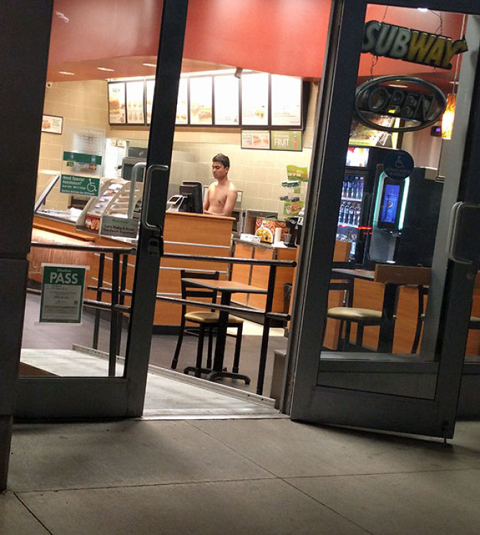 Shirtless man behind a fast-food counter exemplifying indifference.