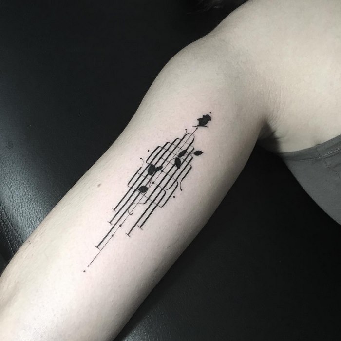 Delicate typographic tattoo by Léo Gavaggio on an arm, featuring abstract black lines and small details.