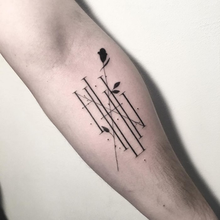 Delicate typographic tattoo on forearm with a floral design intertwined.