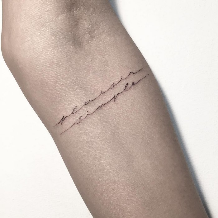 Delicate typographic tattoo by Léo Gavaggio, featuring elegant cursive script on forearm.