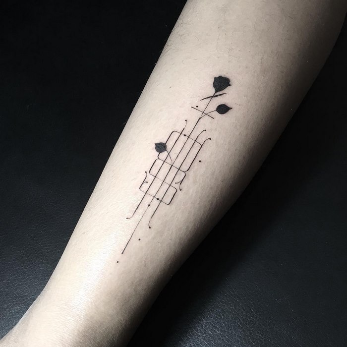 Delicate typographic tattoo by Léo Gavaggio, featuring intricate black ink design on forearm.