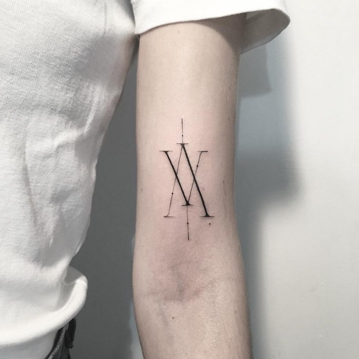 Delicate typographic tattoo by Léo Gavaggio on arm, featuring intricate letter design.