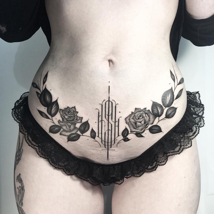 Delicate and sophisticated typographic tattoo with floral design on the abdomen, showcasing Léo Gavaggio's artistry.