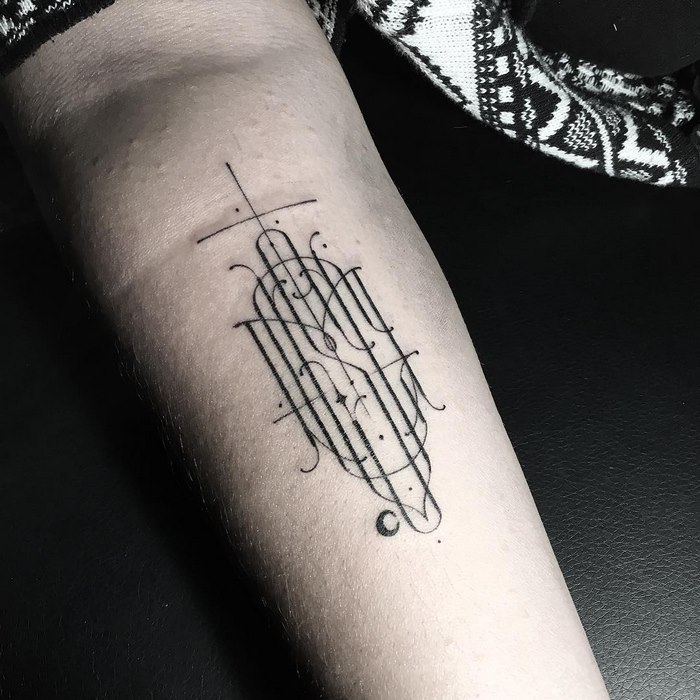 Delicate and sophisticated typographic tattoo in black ink on an arm by Léo Gavaggio.