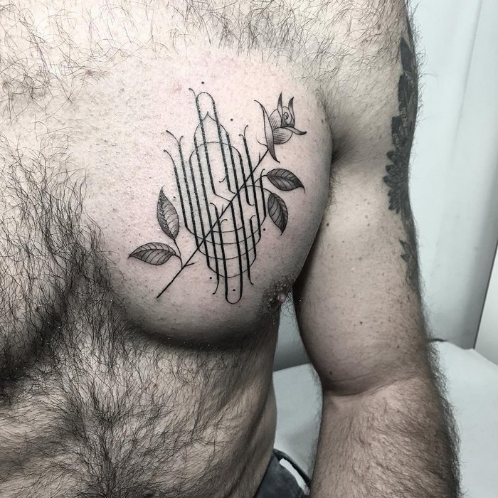 Delicate and sophisticated typographic tattoo by Léo Gavaggio on a person's chest, featuring floral elements.