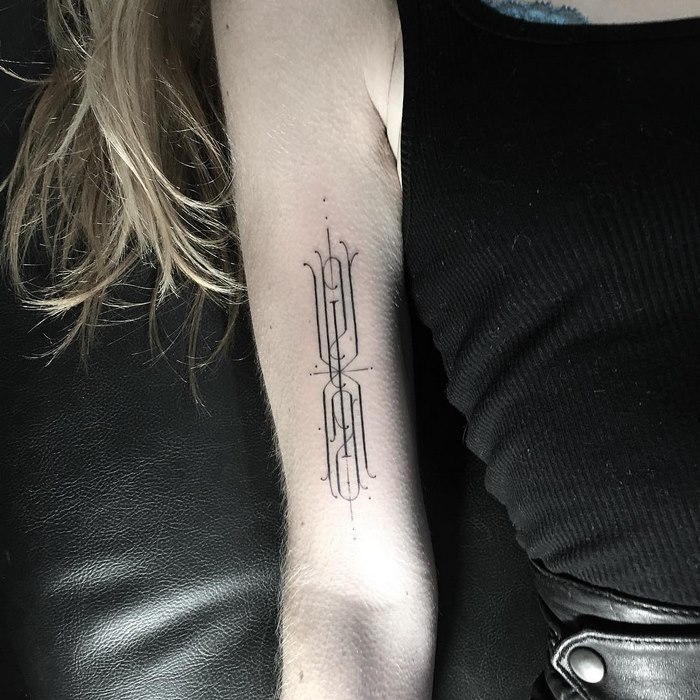 Delicate and sophisticated typographic tattoo by Léo Gavaggio on a person's arm in a minimalist style.