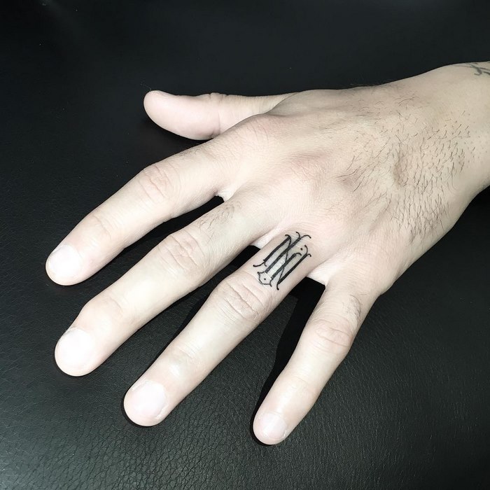 A delicate typographic tattoo on a finger by Léo Gavaggio, showcasing sophisticated design.