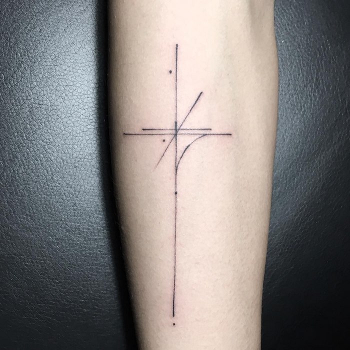 Minimalist typographic tattoo with delicate lines and dots on an arm.