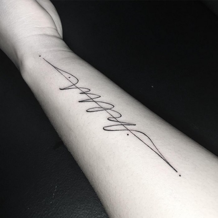 Delicate typographic tattoo on forearm, featuring elegant and sophisticated linework.
