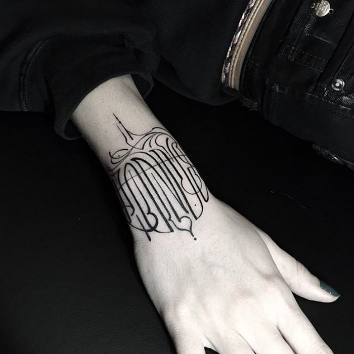 Delicate typographic tattoo on a wrist, featuring intricate and sophisticated design by Léo Gavaggio.