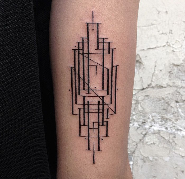 Delicate and sophisticated typographic tattoo design on forearm, featuring geometric lines and shapes.