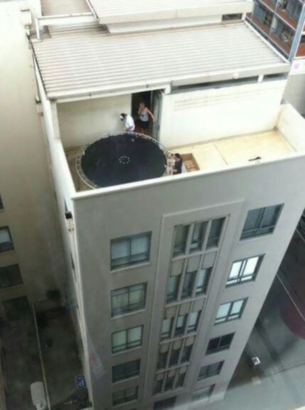 People on a rooftop with a trampoline, illustrating why women live longer than men in daring situations.