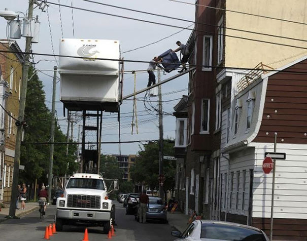 Men engaged in risky behavior, balancing on a pole high above the street, showcasing why women live longer.