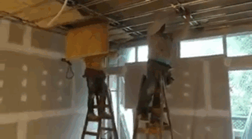 Two men on ladders performing risky ceiling work, illustrating safety differences impacting longevity between genders.
