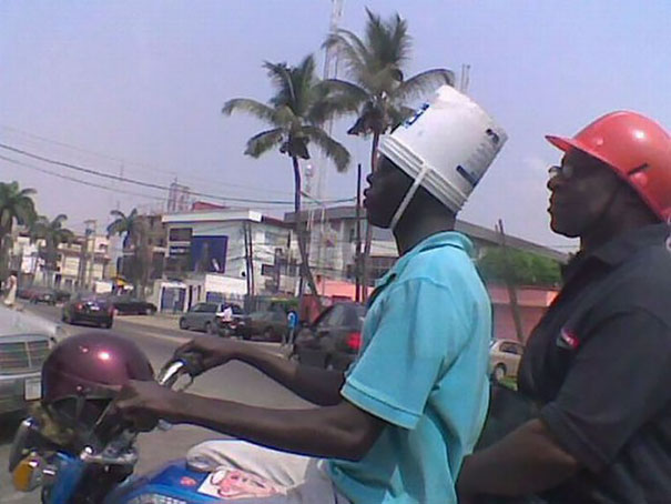 Two men on a motorcycle, one wearing a bucket as a helmet and the other in a hard hat; illustrating gender lifespan humor.
