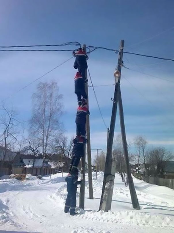 Men climbing a utility pole in the snow, demonstrating risky behavior related to why women live longer.