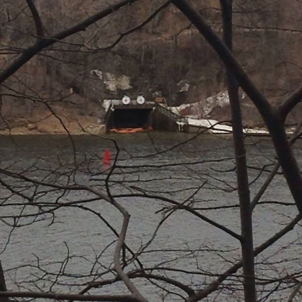 Tunnel entrance across a lake resembling a surprised face with wheels as eyes, an example of funny pareidolia in nature.