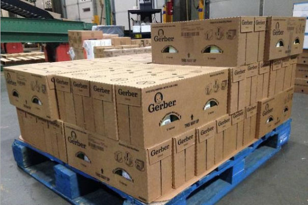 Stacked cardboard boxes on a pallet with cutouts resembling faces, a funny example of pareidolia in everyday objects.
