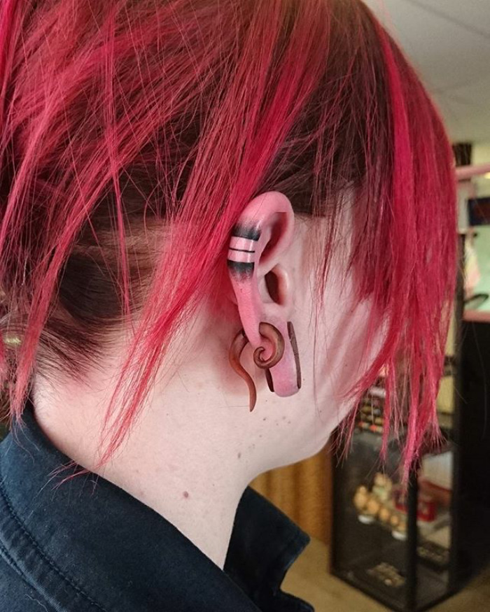 Red-haired person with a black helix tattoo on the ear, showcasing the helix tattoo trend.