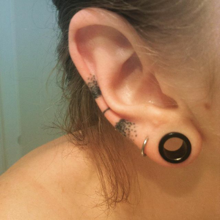 Ear with a helix tattoo and piercings, showcasing the helix tattoo trend.