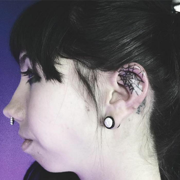 Close-up of a woman's ear with a spiderweb helix tattoo, showcasing the latest Instagram tattoo trend.