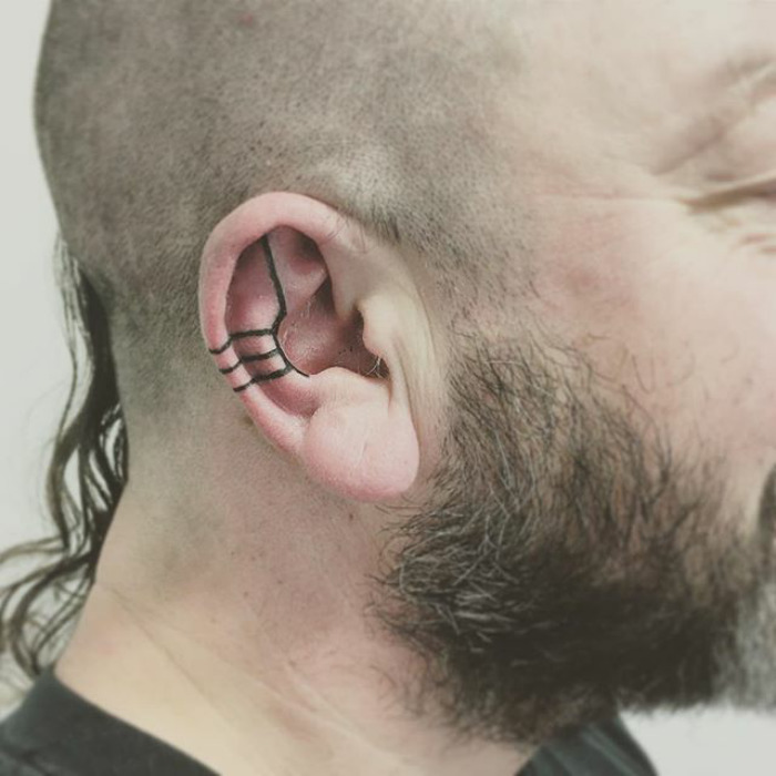 Close-up of a man's ear with a geometric helix tattoo design, showcasing the latest tattoo trend.