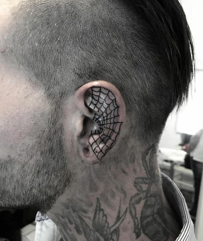 Close-up of a helix tattoo with a spiderweb design on the ear.