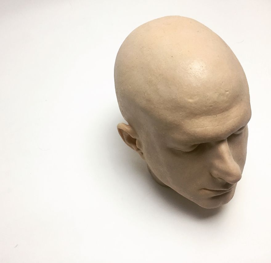 A realistic clay sculpture of a bald head, crafted by a tattoo culture writer exploring creative energy.