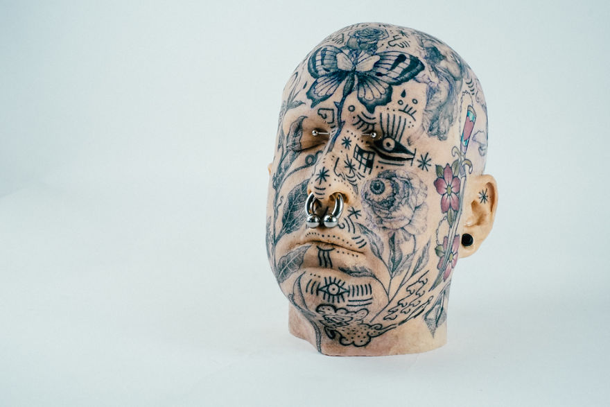 Tattooed mannequin head with intricate designs, showcasing bold creative energy in tattoo culture artistry.