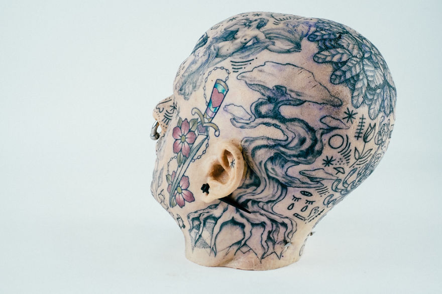 Tattooed mannequin head showcasing intricate designs, highlighting tattoo culture creativity.