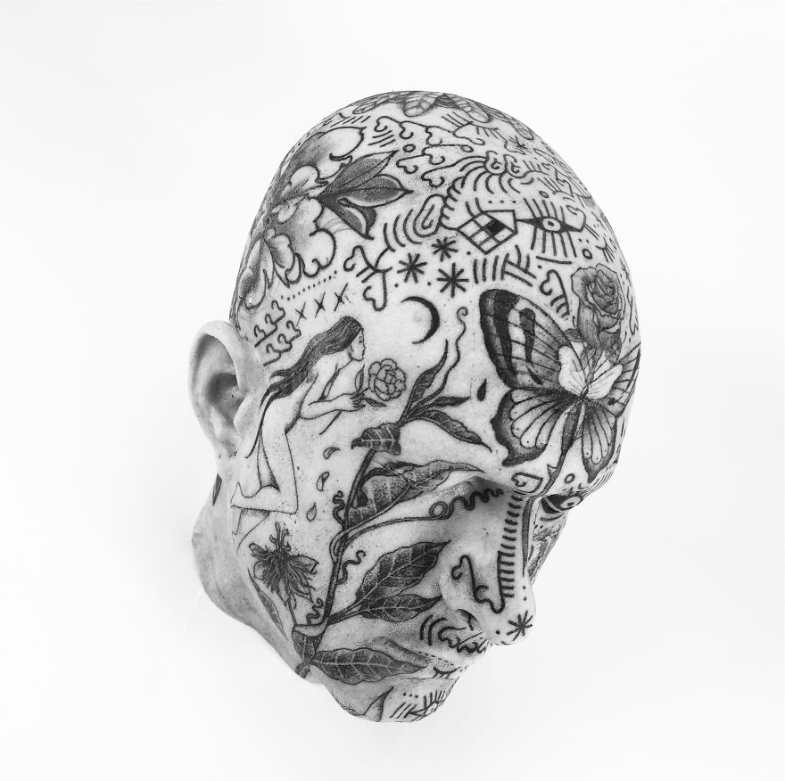 Tattoo culture writer's head with intricate black ink designs, including flowers, a butterfly, and abstract patterns.
