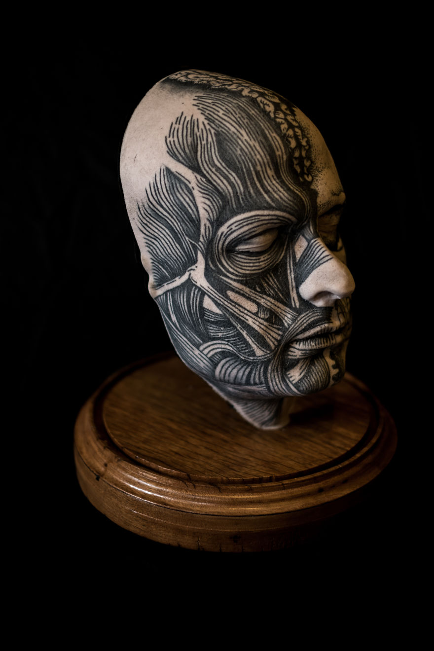 Tattoo culture art sculpture with intricate anatomical details on a wooden base.
