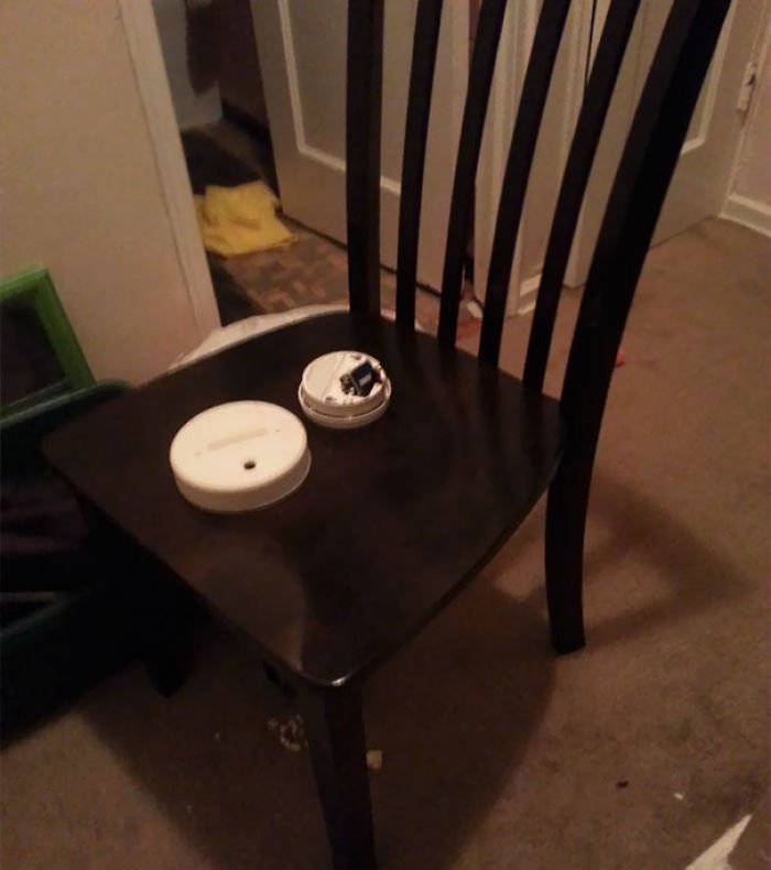 Smoke detector in pieces on a chair, highlighting a humorous relationship mishap.