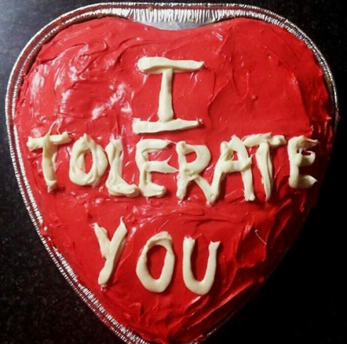 Heart-shaped cake with "I tolerate you" message, humorously showcasing hilarious wives.