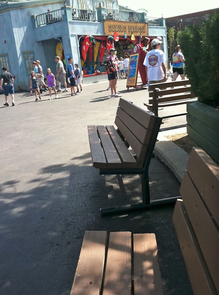 Amusement park scene with benches and people, capturing a lively atmosphere.