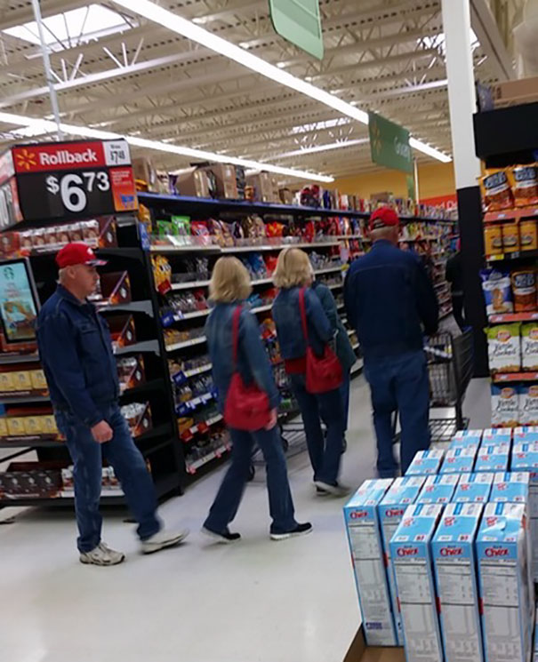 Two womans walking and wearing same blue clothes and red bags
