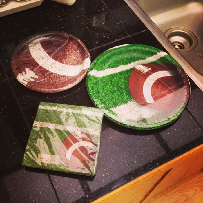 Football-themed plates and napkins on a kitchen counter, humorously designed for football-loving husbands.