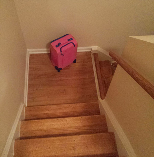 Pink suitcase at the bottom of stairs showing funny pareidolia effect resembling a sad face in everyday objects.